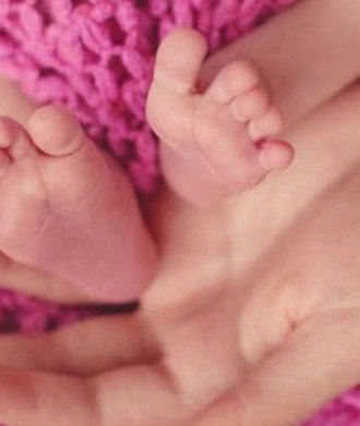 Kleine Babyfüße in den Händen eines Elternteils